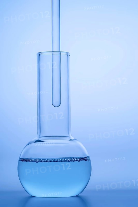 Close-up of a laboratory glass flask filled with blue liquid against a reflective blue surface, highlighting scientific research, chemistry, and experimentation themes