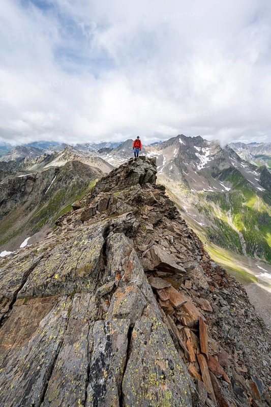Mountaineer on a steep rocky ridge, at the summit of Lasörling, view of mountains of the Venediger group, Lasörling group, Hohe Tauern National Park, East Tyrol, Tyrol, Austria
