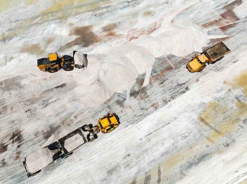 Excavator and lorries and at a harvesting pan of the Walvis Bay Salt works. Aerial view. Drone shot. Walvis Bay, Namibia