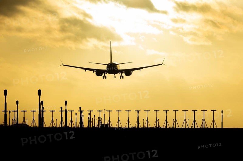 Boeing 737 commercial passenger airliner jet aircraft of Ryanair airways in flight on approach to land over runway lights at sunset at London Stansted airport, Essex, England, United Kingdom