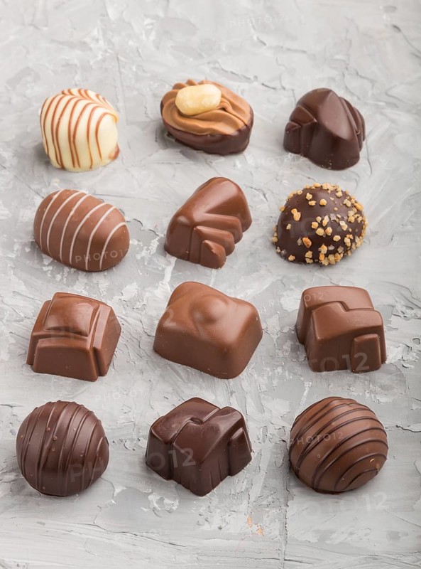 Different chocolate candies on a gray concrete background. side view, close up