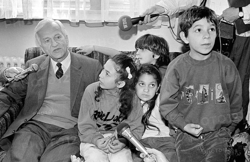 Cologne, DEU - 04.10.1991 - Federal President Richard von Weizsäcker sits next to a family's children in an asylum home and answers questions from reporters, Cologne, Germany