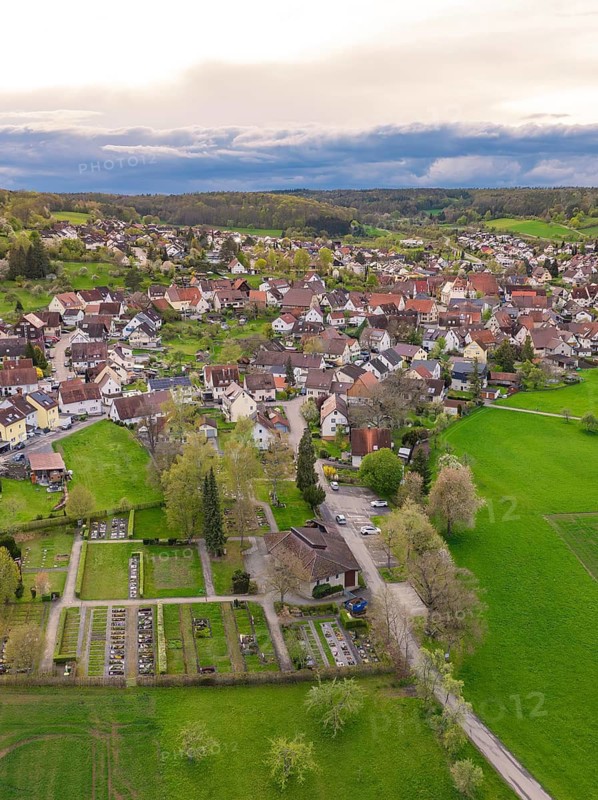 View of a village with gardens and fields, embedded in a green landscape under a cloudy sky, Ostelsheim, district of Calw, Germany