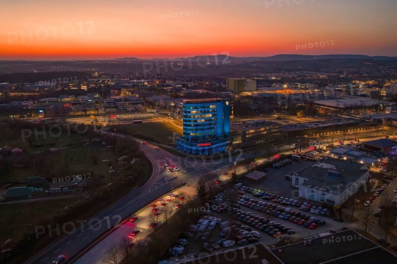 City view in the evening with an illuminated high-rise building and sunset, Porsche, Bietigheim, Germany