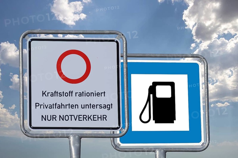 (photo montage) Road sign with information about driving bans and a gas station road sign vacant against a blue sky