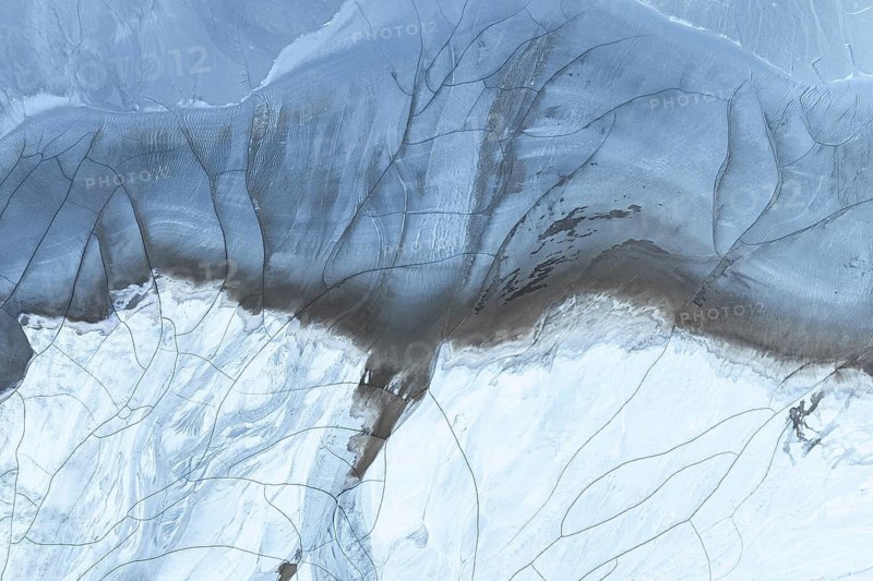 A stunning aerial view showcasing abstract patterns formed by mud and snow in the Arctic region, highlighting nature's unique and intricate designs in a frozen landscape