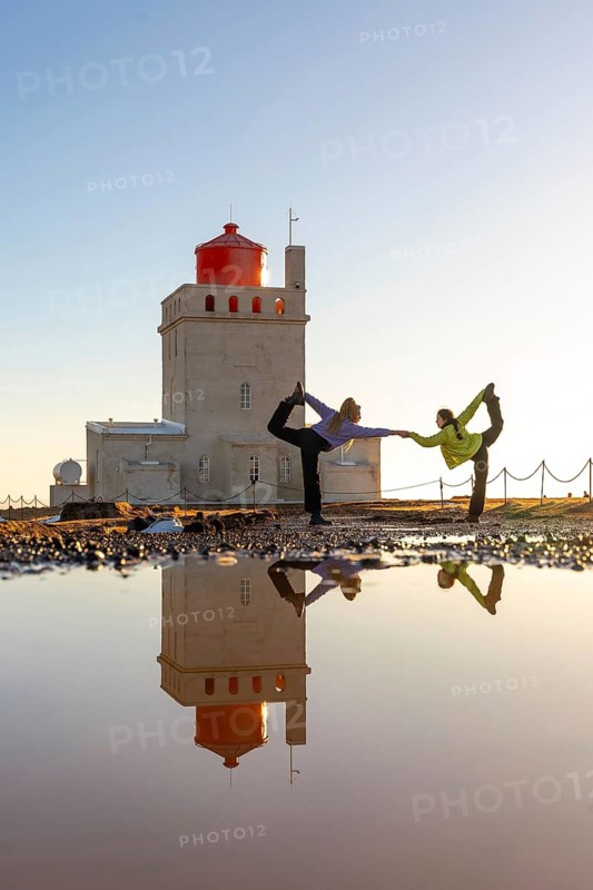 Two women doing yoga at the Dyrholaey Lighthouse in the Icelandic winter