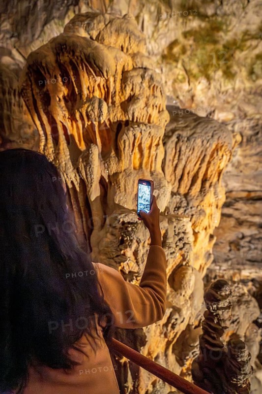 Tourist taking pictures of large stalactites inside postojna cave, a famous tourist attraction in slovenia