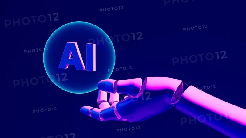 A robotic hand grips a glowing bubble with AI against a dark backdrop, symbolizing progress in artificial intelligence