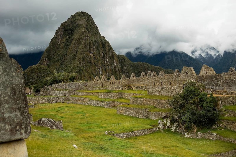 A breathtaking view of the ancient Inca citadel of Machu Picchu in Peru, showcasing lush greenery and the iconic Huayna Picchu looming in the background under overcast skies