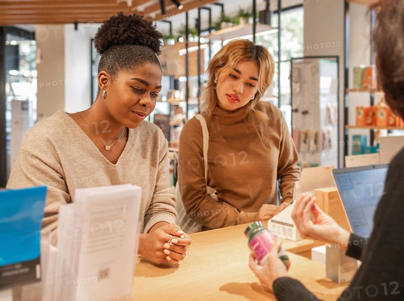 Customers engage with a salesperson in a vibrant cosmetics store, exploring facial products. Shelves display various beauty items, creating an inviting shopping atmosphere