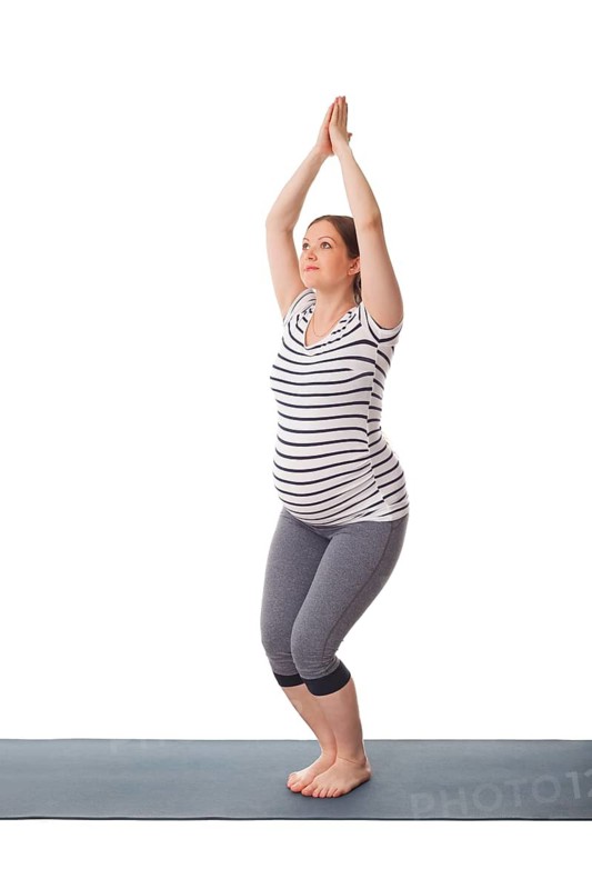 Pregnancy yoga exercise, pregnant woman doing yoga asana Utkatasana chair pose isolated on white background