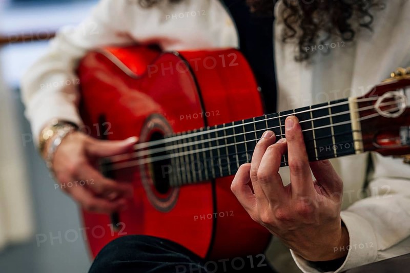 Anonymous Latin man playing red bass guitar in studio