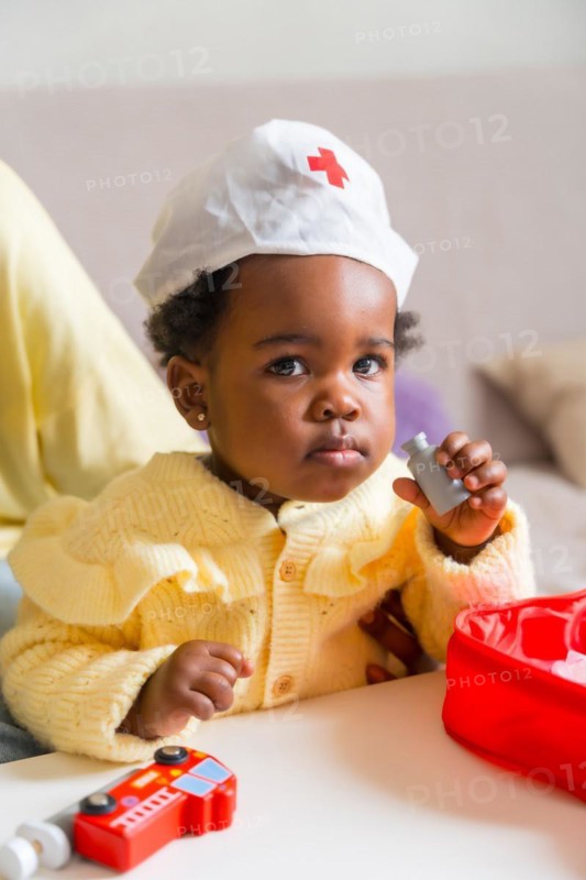 Vertical photo of an adorable african child dressed like doctor playing at home