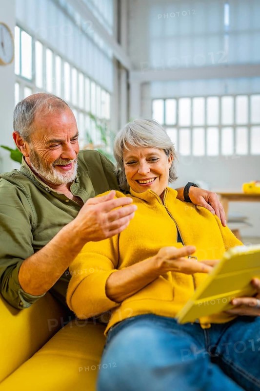 Senior couple reading online news together on the sofa using digital tablet