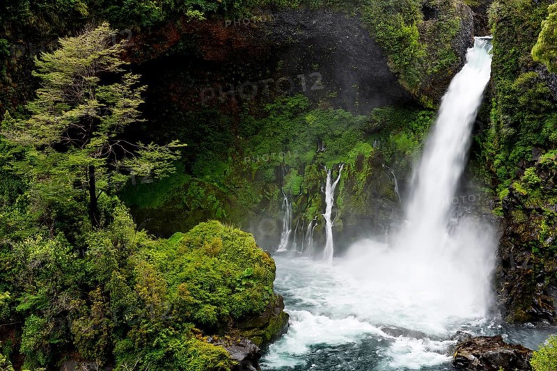 Waterfall falls over mossy basalt rocks in Gumpe, surrounded by dense Valdivian rainforest, Salto Huilo Huilo, Huilo Huilo Biological Reserve, Los Ríos Region, Chile