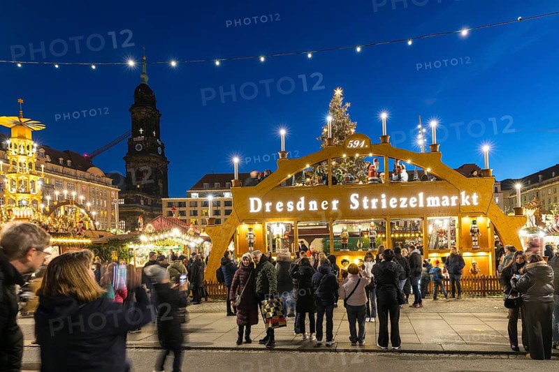 Large walk-in light arch at the entrance to Striezelmarkt, Germany's oldest Christmas market, with the Kreuzkirche tower in the background, Dresden, Saxony, Germany
