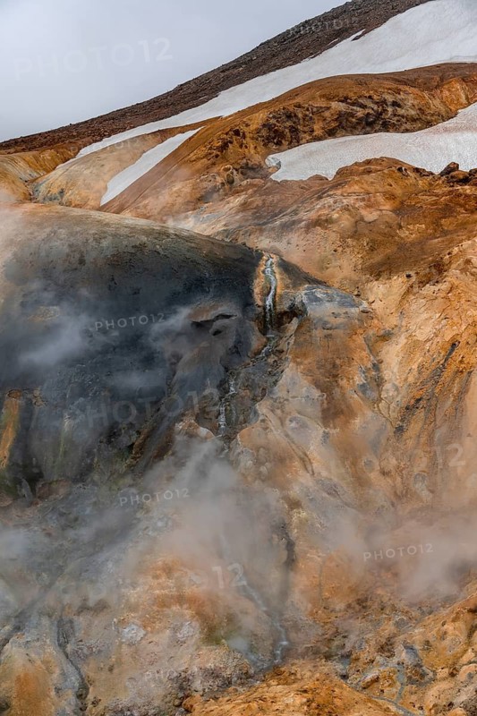 Steaming stream between colourful rhyolite mountains with snowfields, Hveradalir geothermal area, Kerlingarfjöll, Icelandic highlands, Iceland