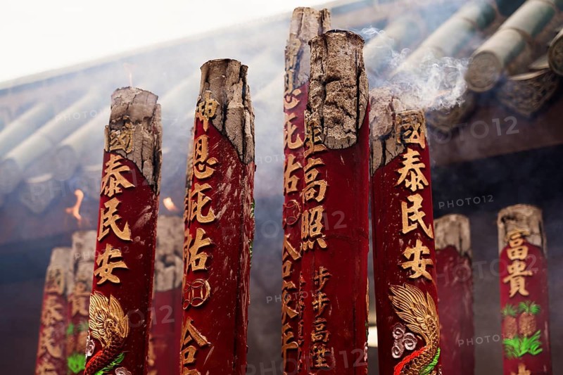 Close-up view of large red incense sticks with detailed carvings, smoldering during the Chinese New Year celebration in Hong Kong