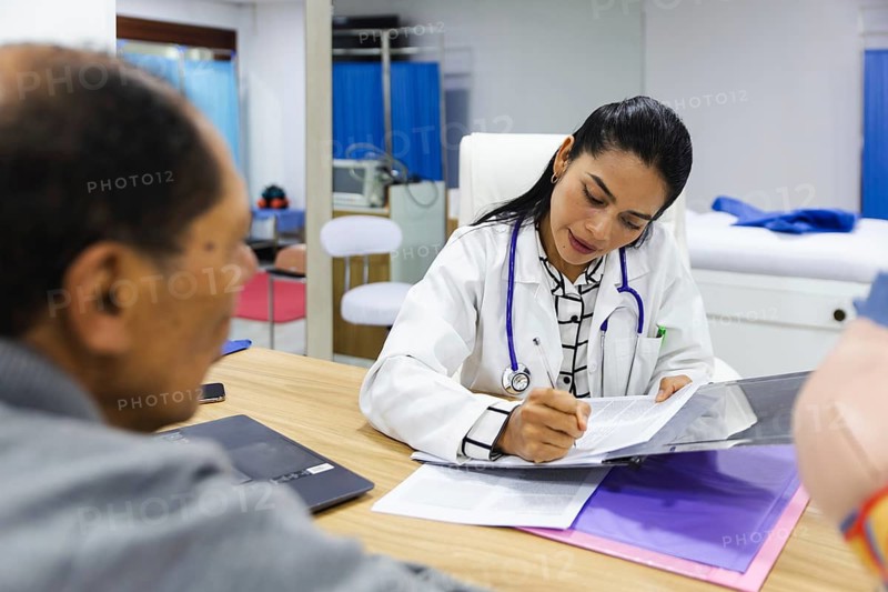 An elderly male patient receives professional care from a young female doctor in a Latin American hospital setting, highlighting compassionate healthcare and patient-doctor interaction