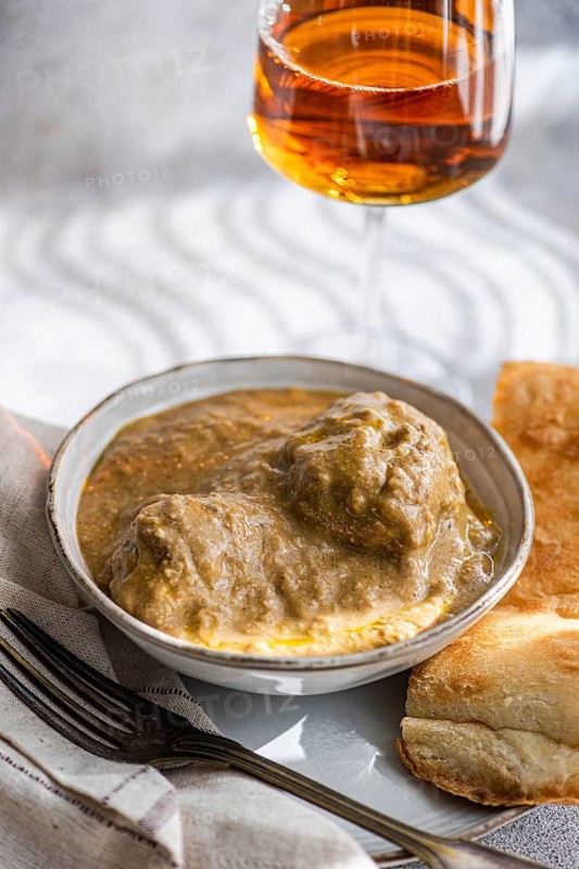 A traditional Georgian dish, Satsivi, features succulent chicken in a rich walnut sauce, elegantly presented with bread and served alongside a glass of rare amber wine