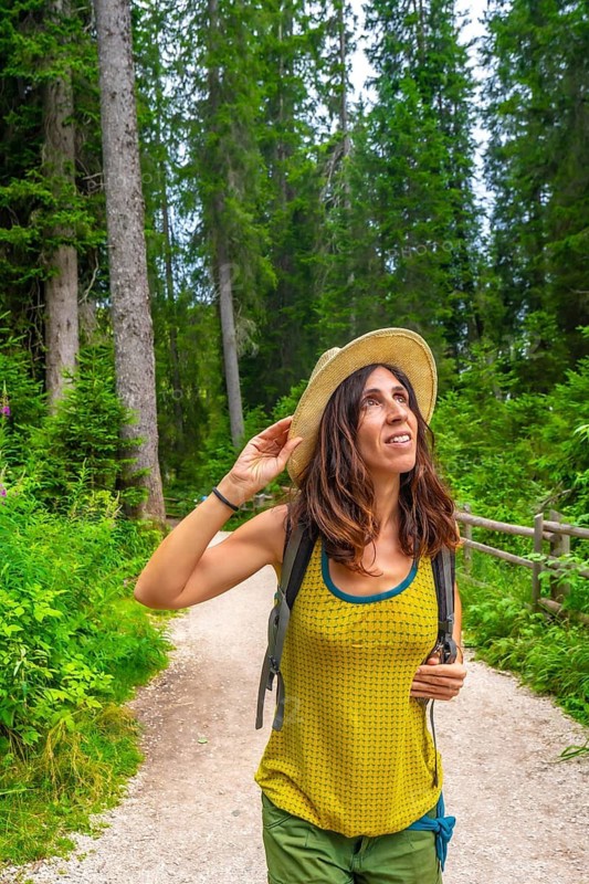 Female tourist enjoying a sunny summer day while hiking along the scenic trails near lake carezza in the stunning dolomites of italy