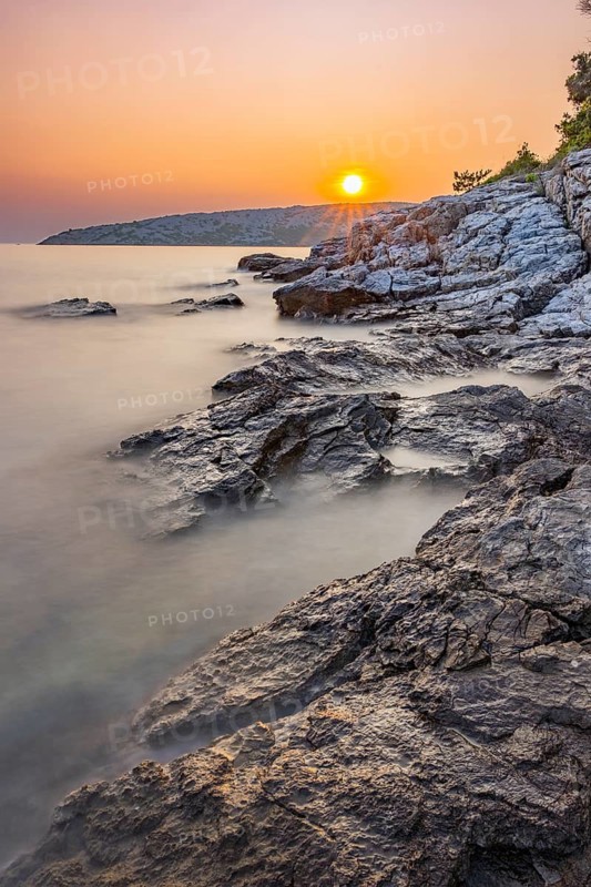 Sunset over crystal clear water on the beach of Ustrine Bay on the island of Cres, long exposure, Croatia
