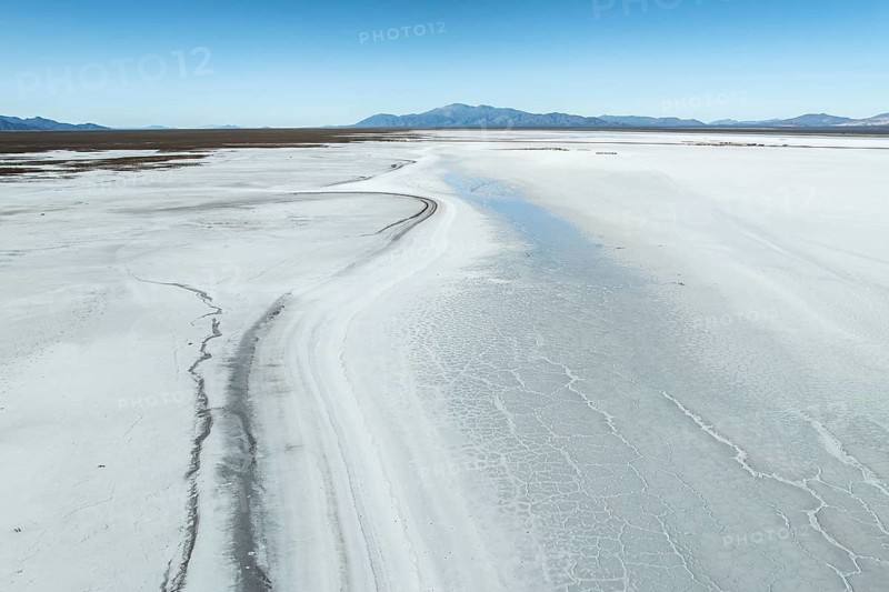Expansive view of the stunning white salt flats of Salinas Grandes, Salta, Argentina, with distant mountains under a clear blue sky, exemplifying the region's natural beauty