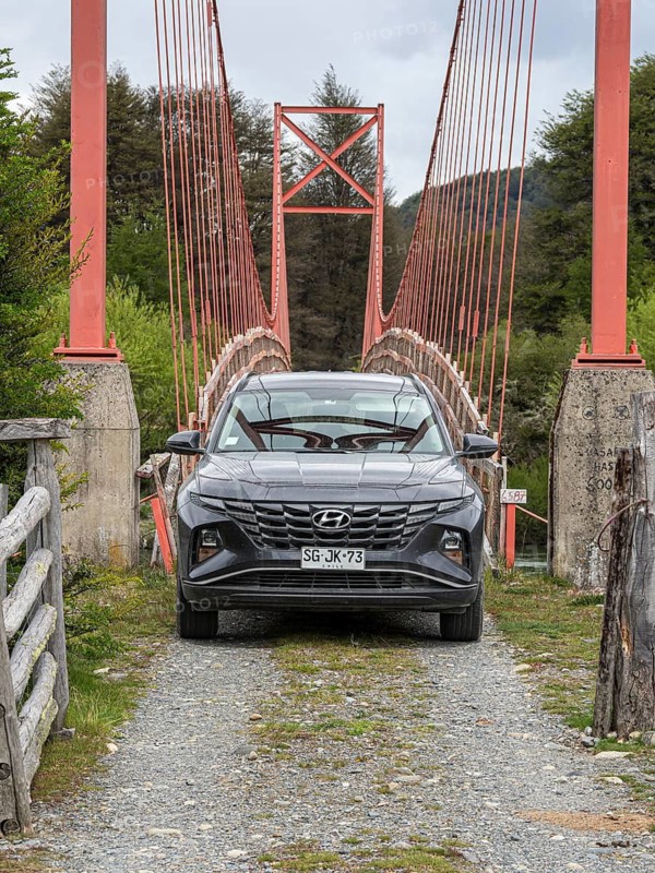 Rental car in front of old-style suspension bridge over river Rio Nadis south of Cochrane, Patagonia, Chile