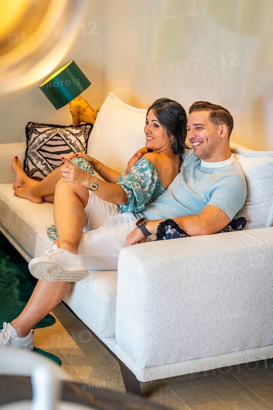 Vertical photo of a happy couple lying on the sofa during movie night