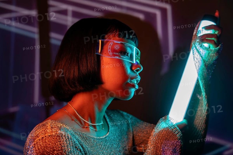 Latin woman immersed in a futuristic setting, wearing cutting-edge virtual reality glasses. The glowing lights create a modern, digital atmosphere, enhancing the tech-savvy vibe