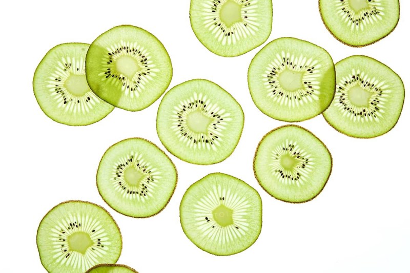 Bright and fresh kiwi slices arranged against a light background, showcasing the fruit vibrant green color and intricate texture. Perfect for themes of health, freshness, and diet