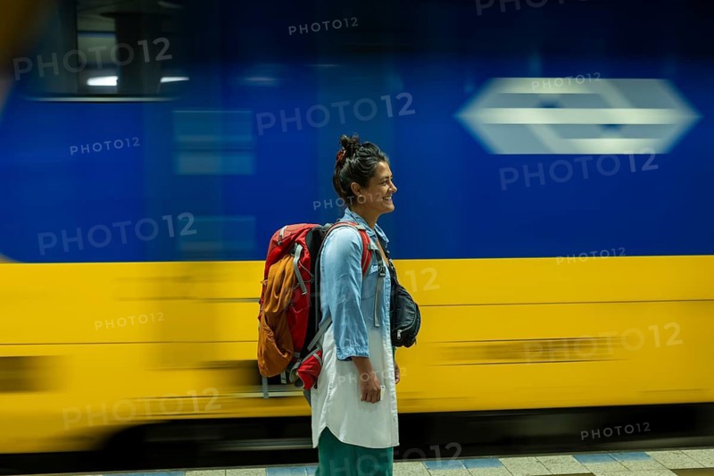 A traveler with a backpack smiles as a train speeds by at a station The scene captures the essence of adventure and the excitement of exploring new places