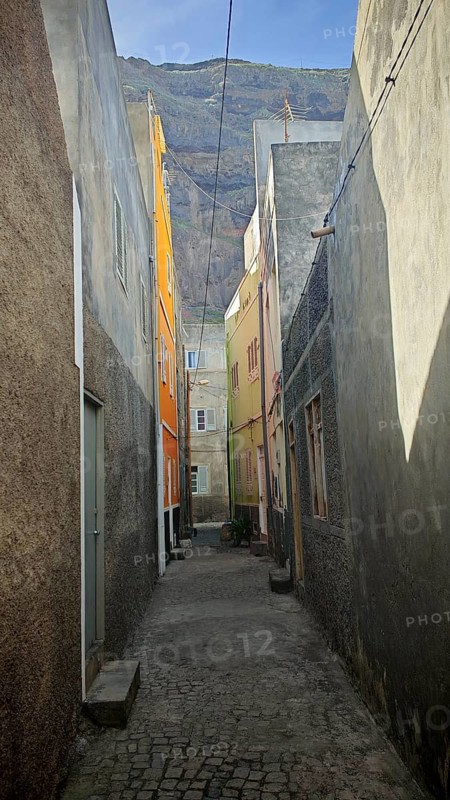 Narrow alley with tall, colorful buildings and a mountain in the background, Ribeira Grande, Santo Antao, Cabo Verde, Cape Verde, Cape Verde