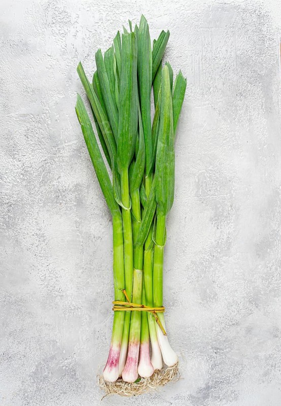 A bunch of young, green garlic, on a light table, top view, no people