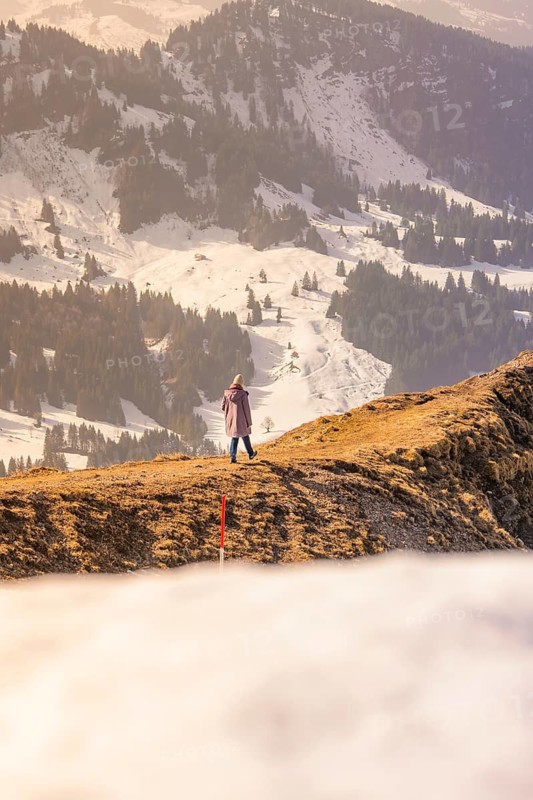 Person standing on snowy mountain enjoying the view of the surrounding winter landscape, Hochgrat Mountains, Allgäu Alps, Oberreute, Germany