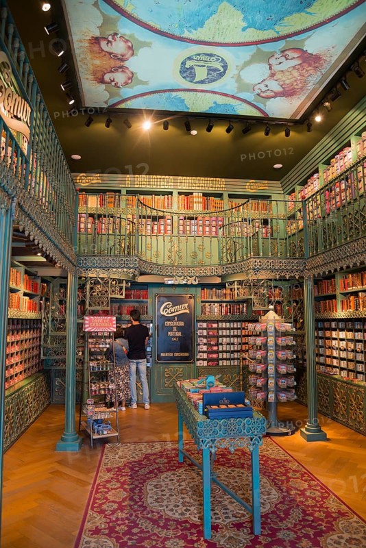 Decorative antique-style shop with bookshelves and shelves full of colourful tins, cosy atmosphere with ornate wooden details and carpet, tins of sardines, tinned sardines, Óbidos, Obidos, Oeste, Centro, Estremadura, Portugal