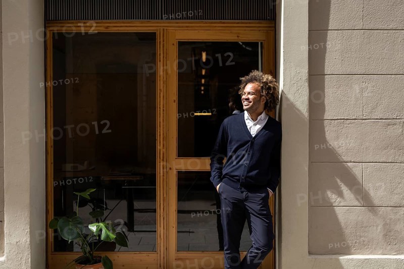 A confident professional enjoys a sunny break outside a trendy coworking space in Barcelona, combining work and leisure in an inspiring and collaborative urban environment