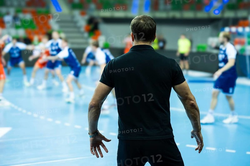 View form the behind on head coach and substitutions bench with handball match in background in Lubin, Poland