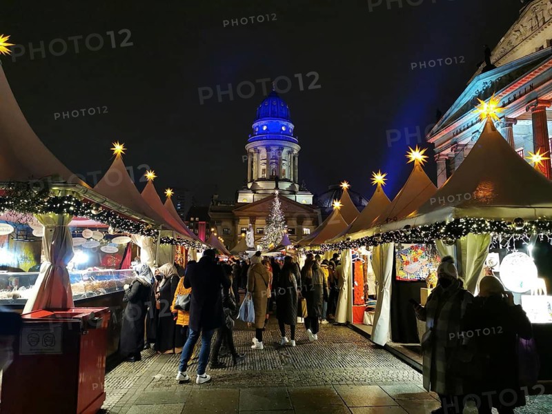 Full Christmas market at Gendarmenmarkt in festive splendor under illuminated tents and lights, Berlin