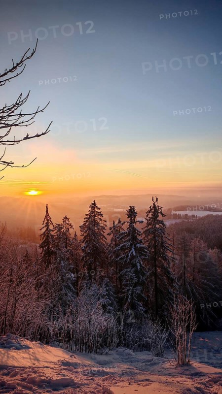 View from Döbra Berg, wide winter landscape with spectacular orange sunset with snow and trees, Franconian Forest nature park Park