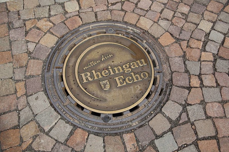 Round manhole cover with the inscription Mitten drin Rheingau Echo, paving stones, soil, Eltville, Rheingau, Taunus, Hesse, Germany