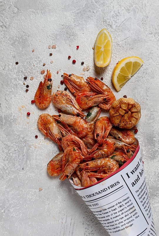 Fried shrimp, in a paper bag, shrimp for beer, in a newspaper, on a gray table, no people