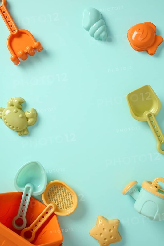 Top view of colorful plastic beach toys frame on blue background with copy space