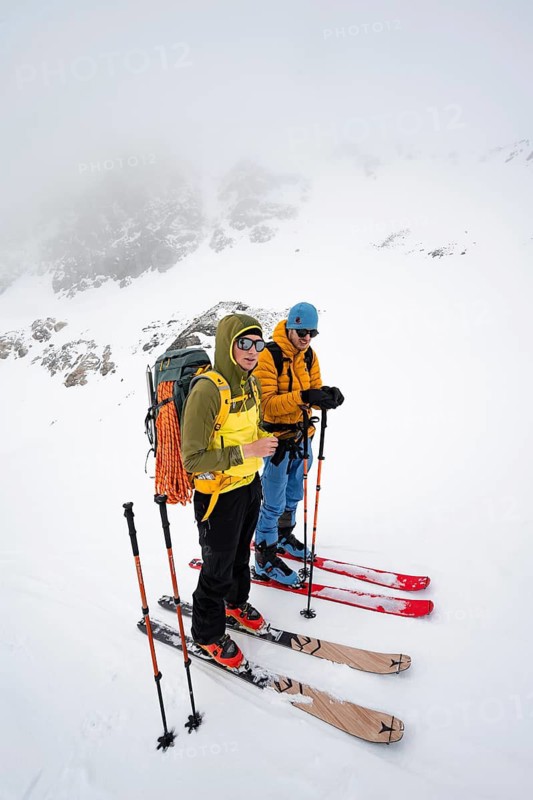 Two ski tourers taking a break, looking for a good ascent route, ski tourers in a wintry mountain landscape with cloudy mountain peaks, ascent to Piz Laviner, Bündner Haute Route, Albula Alps, Rhaetian Alps, Grisons, Eastern Switzerland, Switzerland