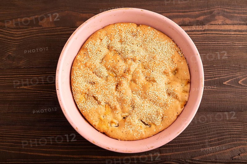 Apple Charlotte cake in baking dish on brown wooden background, top view, flat lay, close up