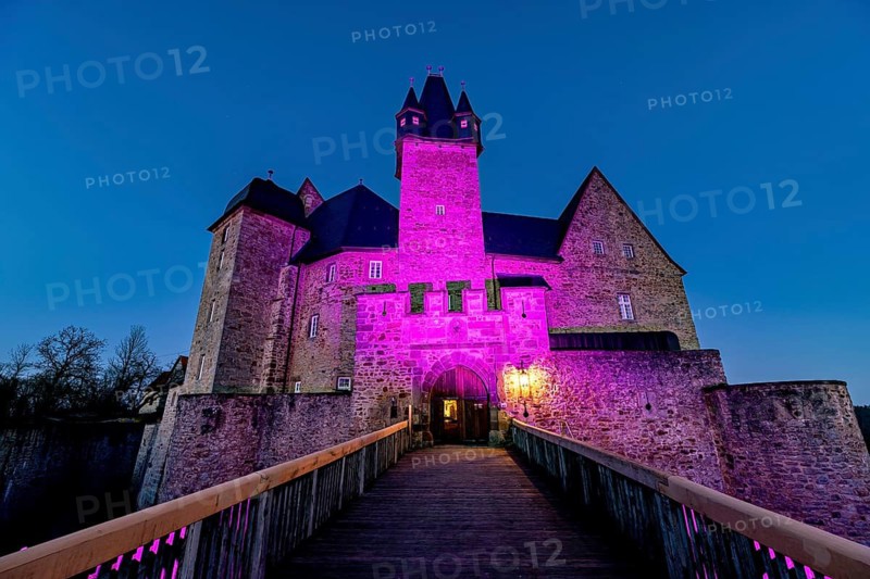 A castle illuminated by pink light at dusk with a bridge in front of it, Spangenberg Castle