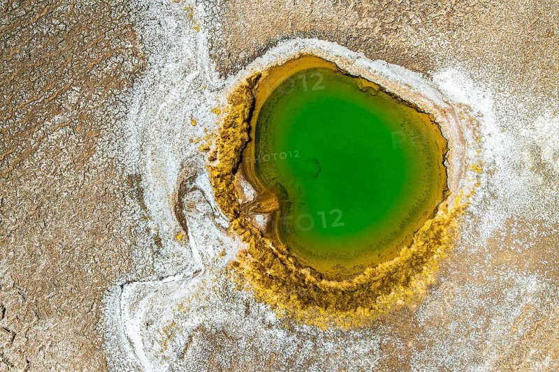 Top view, this drone-captured image shows a striking green lagoon encircled by yellow mineral deposits and arid textures, situated in the expansive Salar de Antofalla in Catamarca Province, Argentina