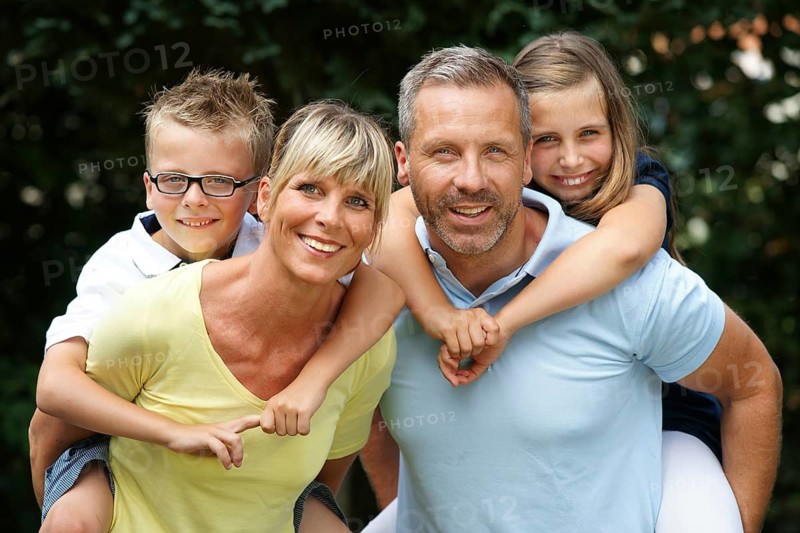 A happy family in the park, four people, man, woman, girl, boy, 8, 9, 35, 45 years piggyback, Hamburg, Federal Republic of Germany