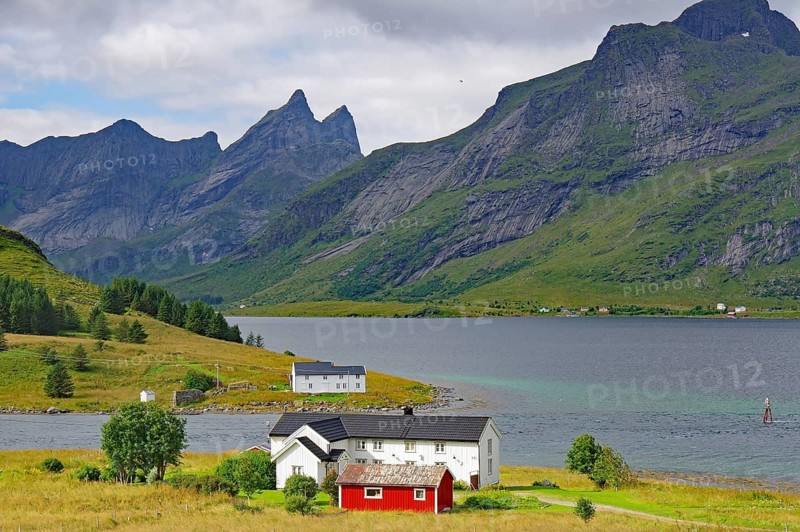 An idyllic valley with houses surrounded by high mountains under cloudy skies, Lofoten, Nordland, Arctic, Norway